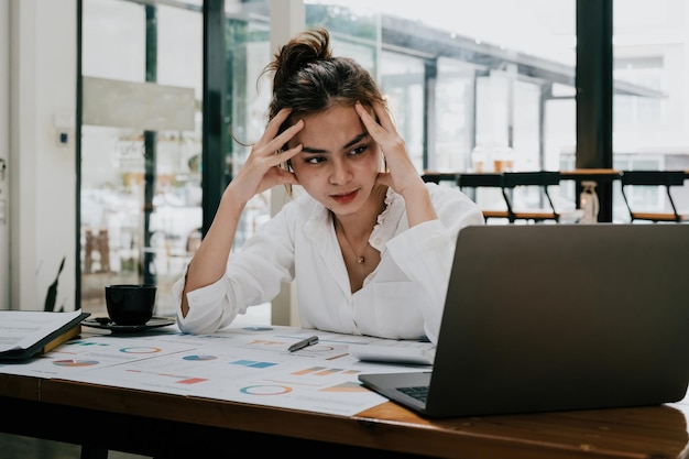 Femme d'affaires mixte fatiguée avec des maux de tête au bureau se sentant malade au travail