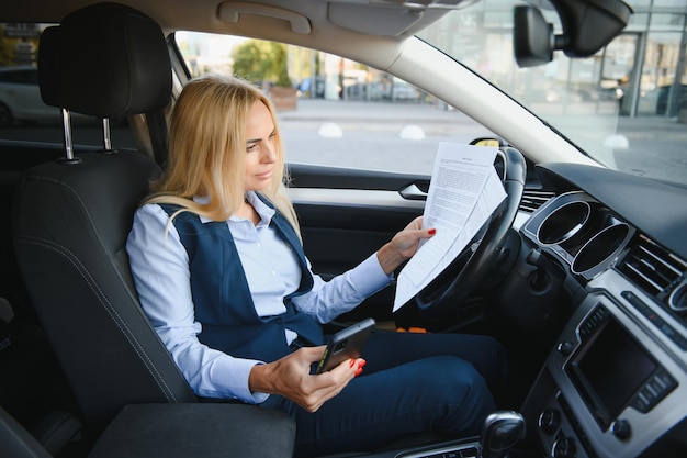 Femme d'affaires de mode avec des papiers financiers près de sa voiture