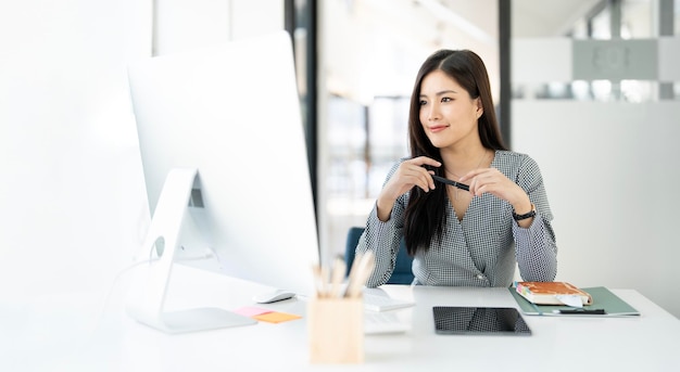 Une femme d'affaires moderne dans le bureau souriante et regardant l'écran du moniteur