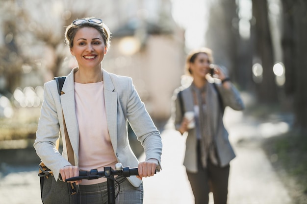 Une femme d'affaires mûre faisant du scooter électrique en se rendant au travail.