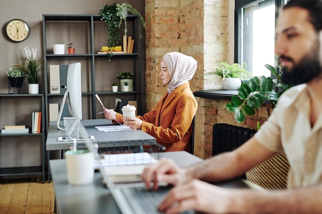 Femme d'affaires musulmane contemporaine analysant des données financières dans des documents