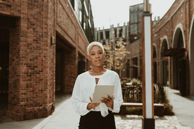 Femme d'affaires noire avec une tablette numérique dans la ville