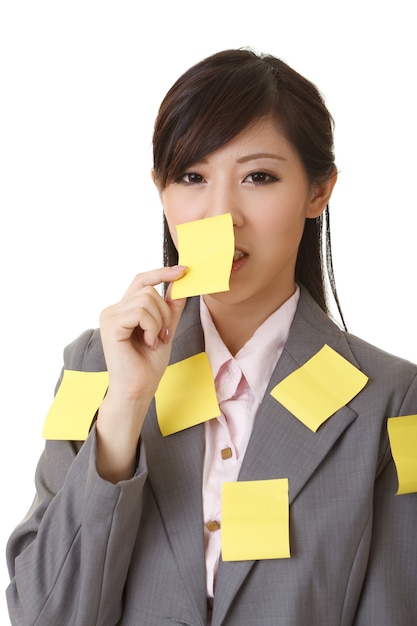 Femme d'affaires avec de nombreuses notes de mémo jaune sur son corps, portrait agrandi.