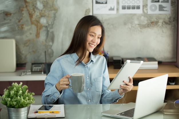 Femme d&#39;affaires de nouvelle génération travaille avec une tablette, femme asiatique travaillent heureusement au bureau