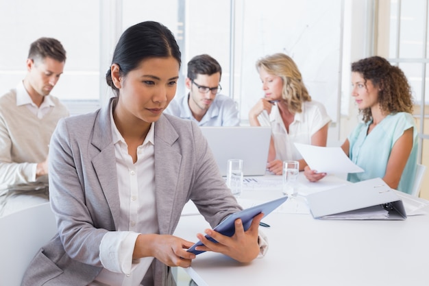 Femme d&#39;affaires occasionnel à l&#39;aide de sa tablette lors d&#39;une réunion