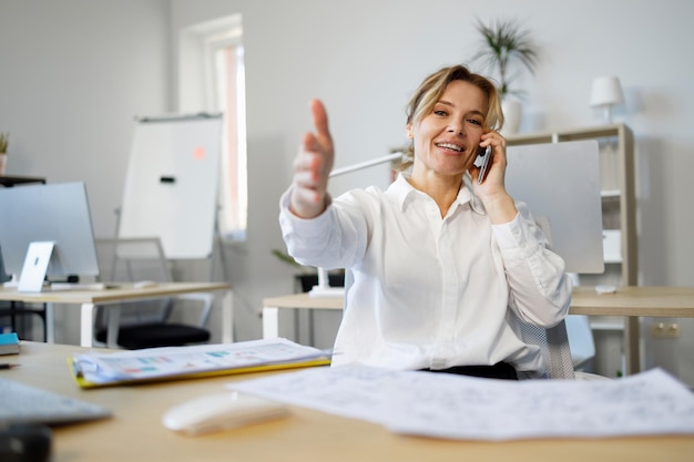 Femme d'affaires occupée parlant au téléphone et pointant vers la caméra