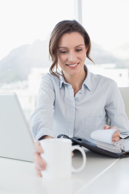 Femme d&#39;affaires avec ordinateur portable et agenda au bureau