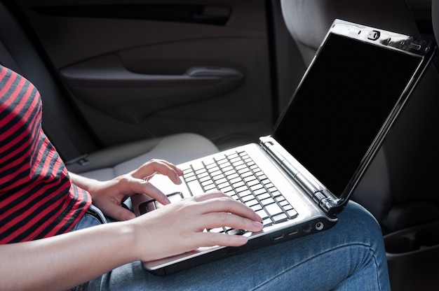 Femme d'affaires avec ordinateur portable dans la voiture