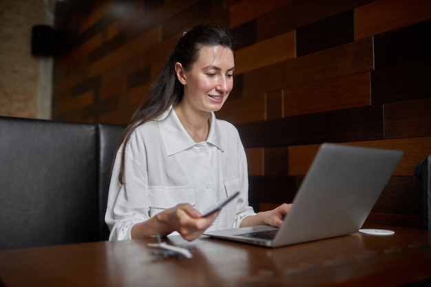 Femme d'affaires avec ordinateur portable. Elle travaille et se détend dans un café en buvant du café au lait