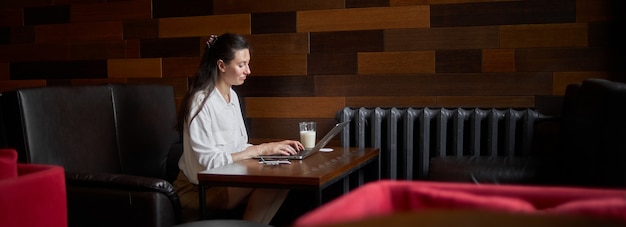 Femme d'affaires avec ordinateur portable. Elle travaille et se détend dans un café en buvant du café au lait