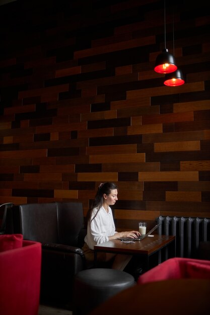 Femme d'affaires avec ordinateur portable. Elle travaille et se détend dans un café en buvant du café au lait