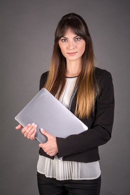 Femme d'affaires avec un ordinateur portable sur fond gris