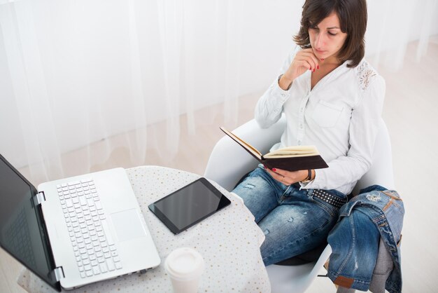 Femme d'affaires avec ordinateur portable et journal intime dans un bureau lumineux travail indépendant à la maison