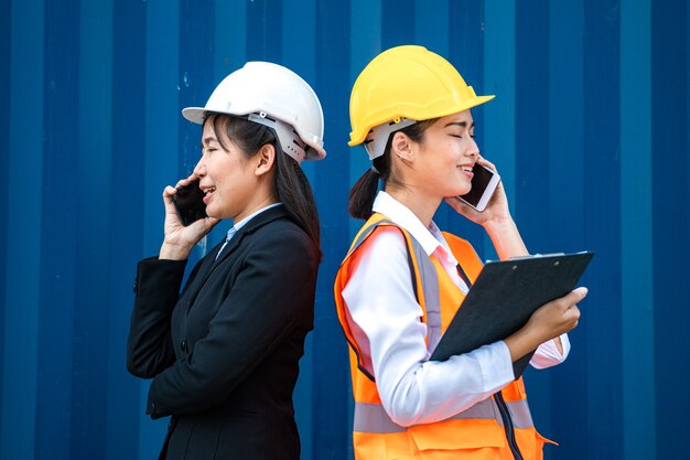 Femme d'affaires et ouvrier d'usine parlant au téléphone devant le conteneur