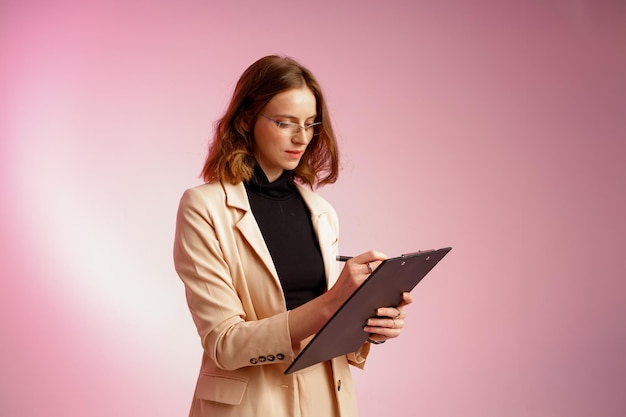 Femme d'affaires avec des papiers sur fond rose portant des lunettes Résoudre des tâches importantes au bureau