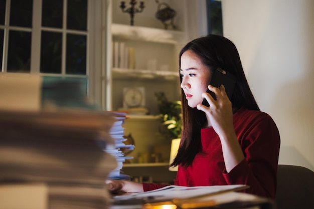 Femme d'affaires parlant affaires par téléphone pendant les heures supplémentaires au bureau à domicile