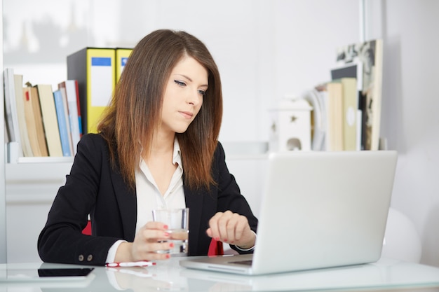 Femme d'affaires parlant au mobile et travaillant au bureau avec ordinateur portable