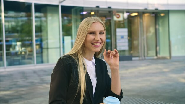 Femme d'affaires parlant au téléphone et agitant la main.