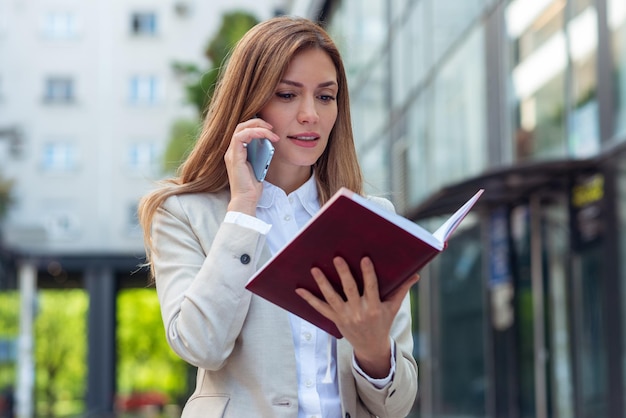 Femme d'affaires parlant au téléphone et regardant son ordinateur portable en plein air