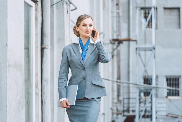 Une femme d'affaires parle au téléphone à l'extérieur du bâtiment.