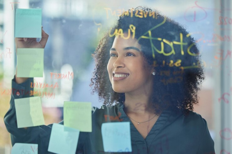 Photo femme d'affaires planifiant et écrivant avec un verre collant et une stratégie pour la recherche marketing dans une entreprise de publicité employé d'entreprise heureux et analyse du plan d'innovation et vision de l'entreprise