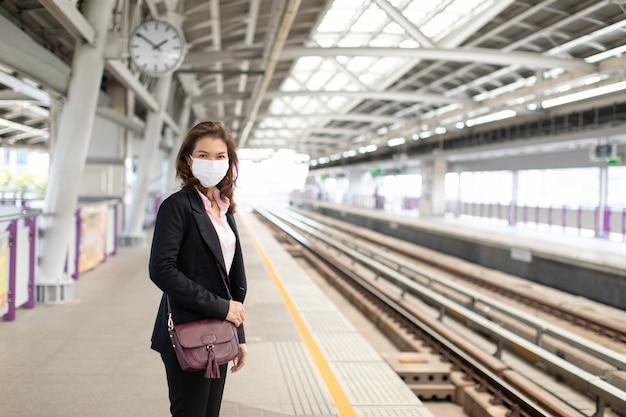 Femme d'affaires portant un masque en attente de train.