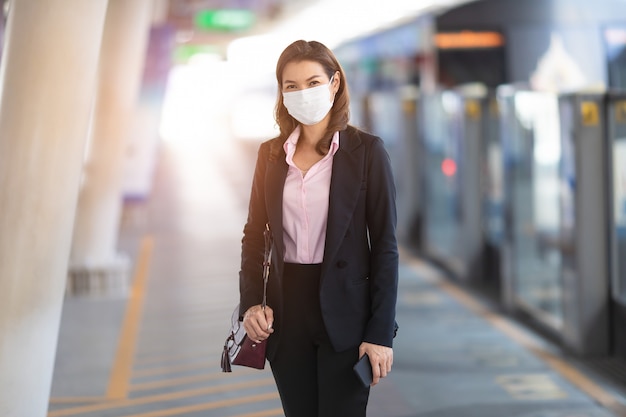 Femme d'affaires portant un masque en attente de train.