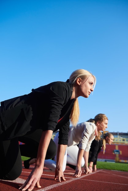 femme d'affaires en position de départ prête à courir et à sprinter sur une piste de course d'athlétisme