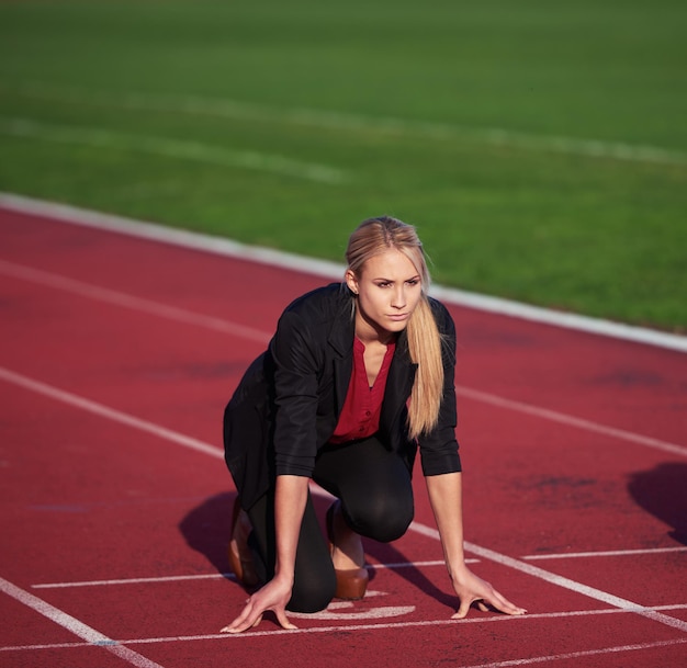 femme d'affaires en position de départ prête à courir et à sprinter sur une piste de course d'athlétisme