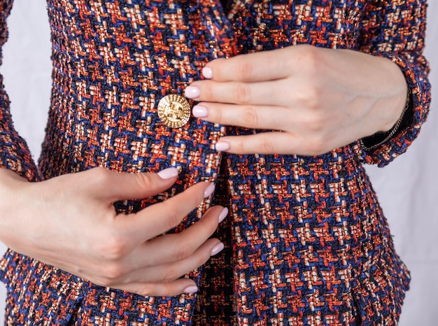 Une femme d'affaires positive attache un bouton à sa veste en tweed