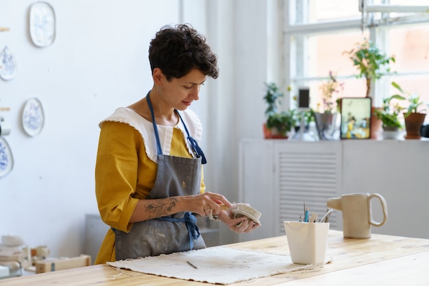 Une femme d'affaires en poterie fabrique des céramiques à vendre et pour enseigner l'art aux étudiants en atelier