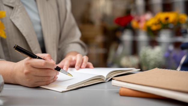 Une femme d'affaires prenant des notes ou écrivant quelque chose dans son livre tout en travaillant à distance dans un café