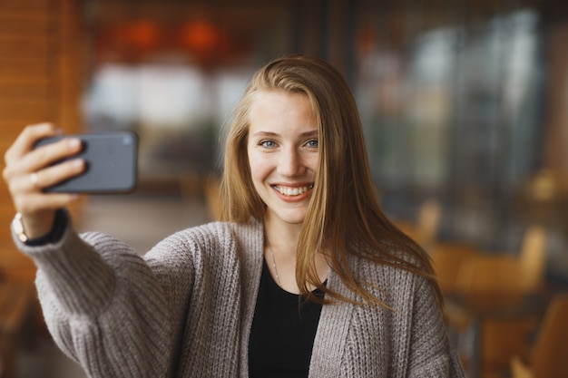 Femme d'affaires prenant une photo de selfie à l'aide d'une application pour téléphone intelligent sur un smartphone pour les médias sociaux. Jeune femme d'affaires utilisant un smartphone souriant heureux portant une veste de costume à l'extérieur. Professionnel féminin urbain.