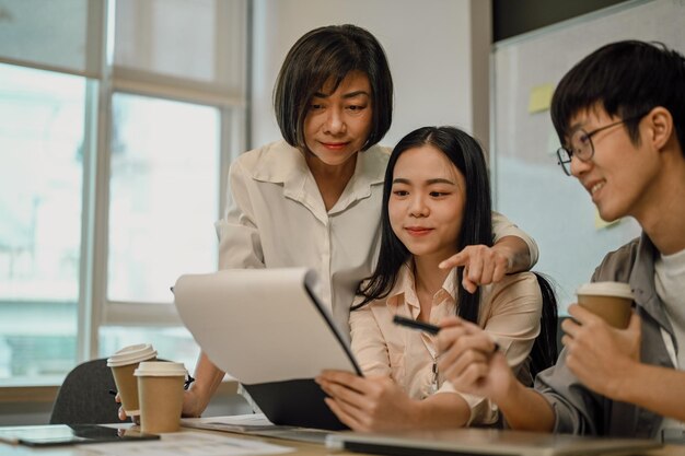 Une femme d'affaires professionnelle analysant des données de marketing avec des collègues plus jeunes au bureau.