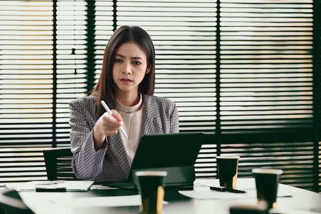 Femme d'affaires professionnelle utilisant un ordinateur portable et travaillant avec un document sur le bureau