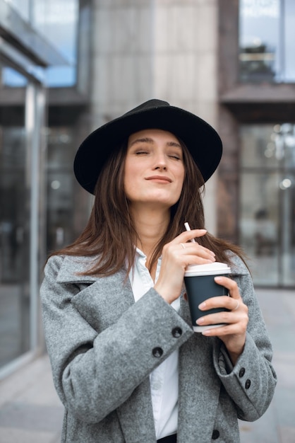 Une femme d'affaires profite d'une pause café avec une boisson chaude à la main.