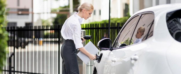 Une femme d'affaires progressiste branche la prise du chargeur de la station de charge à l'EV