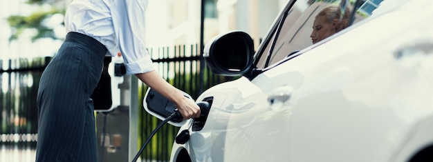 Femme d'affaires progressiste en gros plan avec véhicule électrique à la station de charge