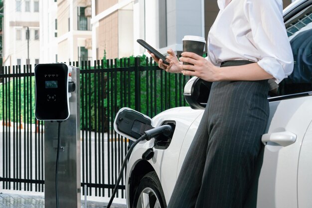 Femme d'affaires progressiste en gros plan avec véhicule électrique à la station de charge