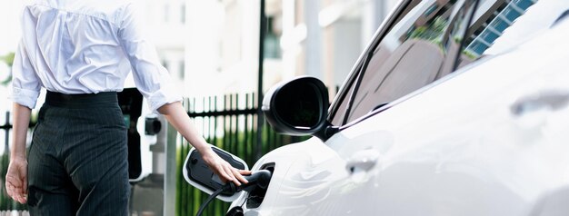 Femme d'affaires progressiste en gros plan avec véhicule électrique à la station de charge