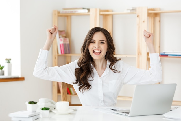 Femme d'affaires prospère avec les bras assis dans un bureau moderne