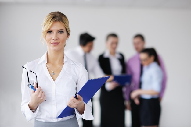 Femme d'affaires prospère debout avec son personnel en arrière-plan dans un bureau moderne et lumineux