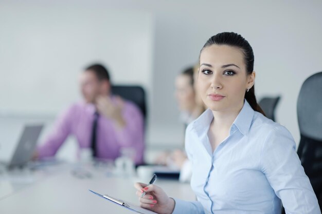 Femme d'affaires prospère debout avec son personnel en arrière-plan dans un bureau moderne et lumineux