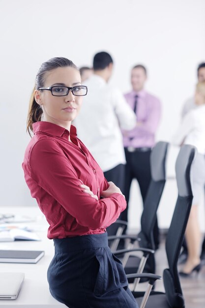 Femme d'affaires prospère debout avec son personnel en arrière-plan dans un bureau moderne et lumineux