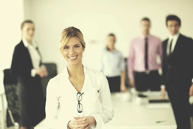 Femme d'affaires prospère debout avec son personnel en arrière-plan dans un bureau moderne et lumineux