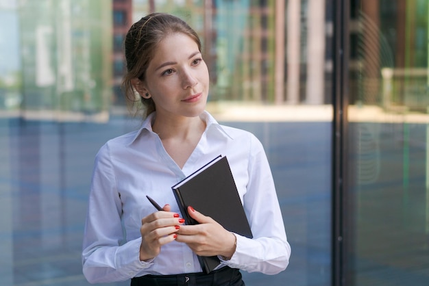 Femme d'affaires prospère prenant des notes tout en marchant à l'extérieur