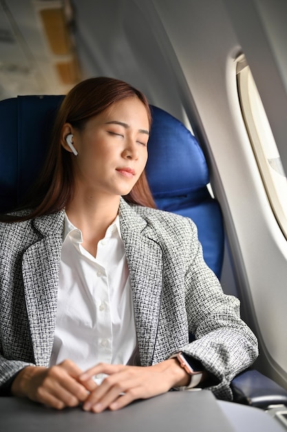 Une femme d'affaires prospère s'est détendue en faisant une sieste les yeux fermés en volant quelque part en avion