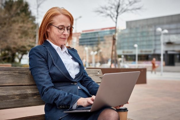 Femme d'affaires puissante prenant en charge l'extérieur avec son ordinateur portable