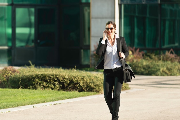 Une femme d'affaires qui marche et utilise un téléphone portable.