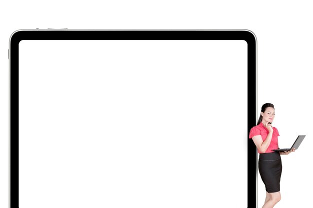 Une femme d'affaires réfléchie appuyée sur une grande tablette